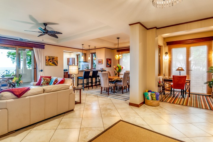 Spacious open-plan living room and dining area with modern furnishings and a view of a lush garden.
