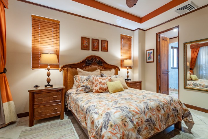 Cozy bedroom with floral bedding, wooden furniture, and warm lighting.