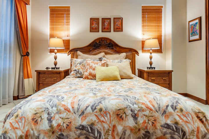 Cozy bedroom with floral bedspread, wooden bed frame, and matching nightstands with lamps.