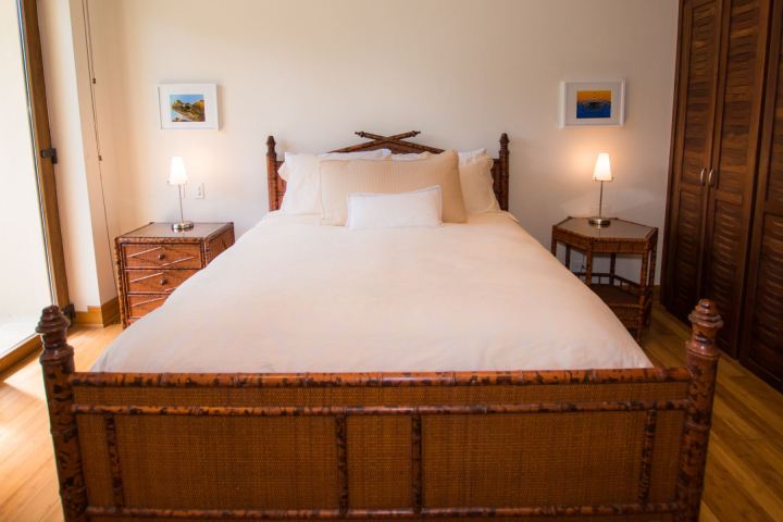 Bedroom with a wooden bed, white bedding, two lamps, and framed artwork on the wall.