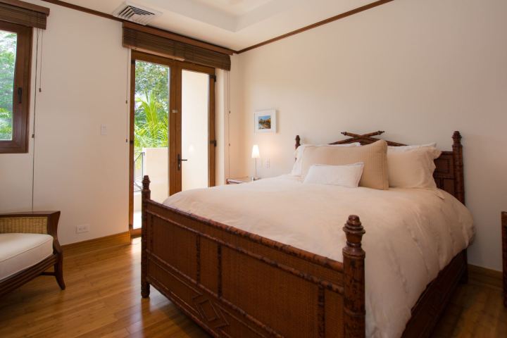 Cozy bedroom with wooden furniture, large bed, and balcony view.