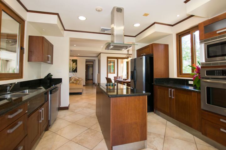 Modern kitchen with wooden cabinets, stainless steel appliances, and an island in the center.