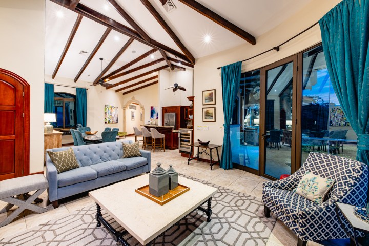Luxurious living room with vaulted ceiling, blue curtains, and modern furniture.