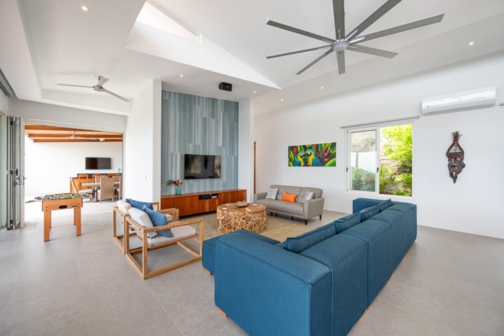 Spacious living room with blue sofa, TV, ceiling fan, and modern decor.