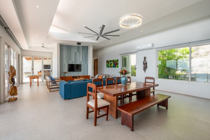Spacious modern living room with dining table, blue sofa, and large windows.