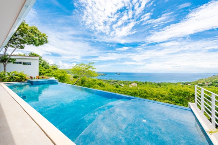 Infinity pool overlooking a scenic ocean view with blue sky.