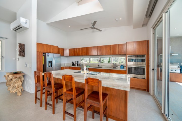 Modern kitchen with wooden cabinets, island, stainless steel appliances, and ceiling fan.