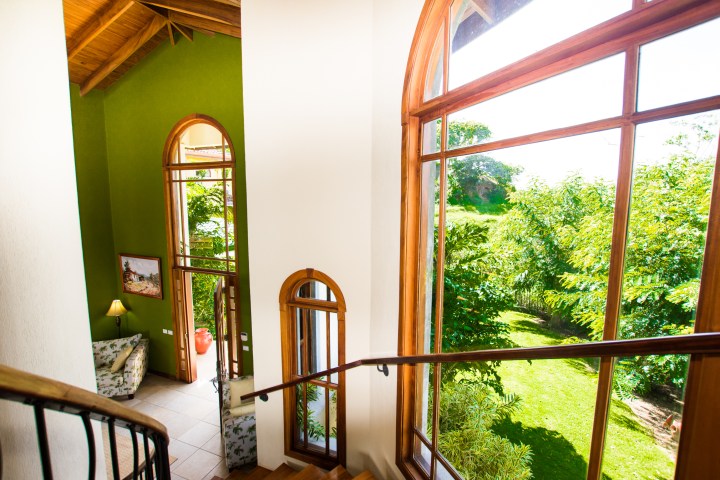 Interior with large windows, green walls, and staircase overlooking a garden.