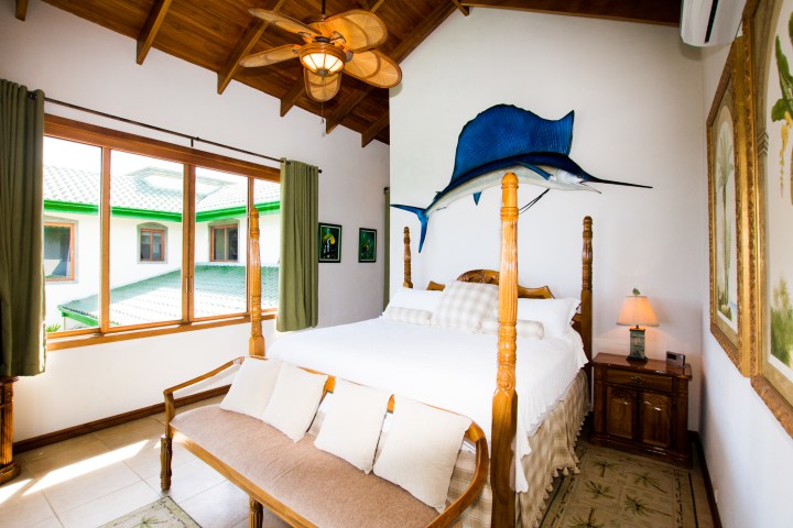 Bedroom with a wooden canopy bed and a mounted blue marlin on the wall.