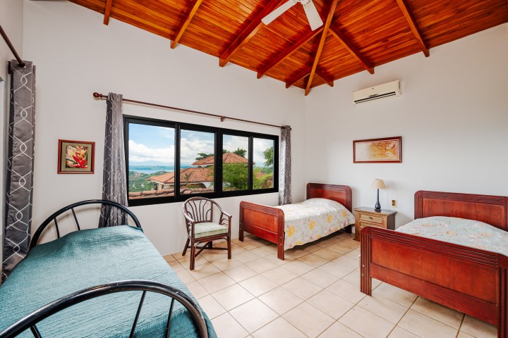 Room with vaulted wood ceiling, two wooden beds, a daybed, and a window with scenic view.