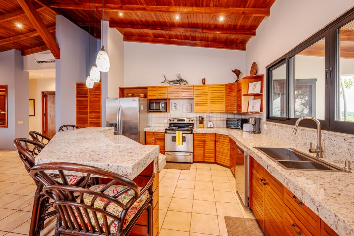 Wood-paneled kitchen with island, barstools, stainless appliances, and granite countertops.