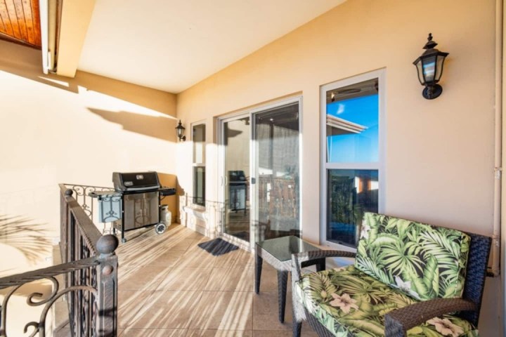 Covered patio with a grill, patterned sofa, table, and glass doors leading inside.