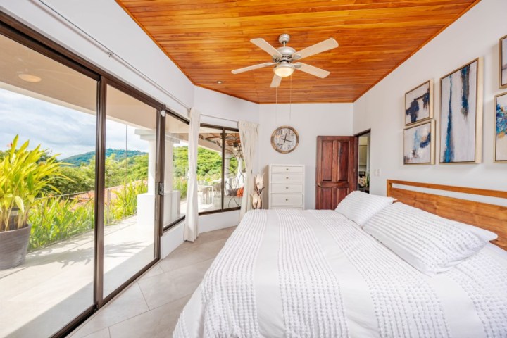 Bright bedroom with wooden ceiling, large windows, and a scenic view.