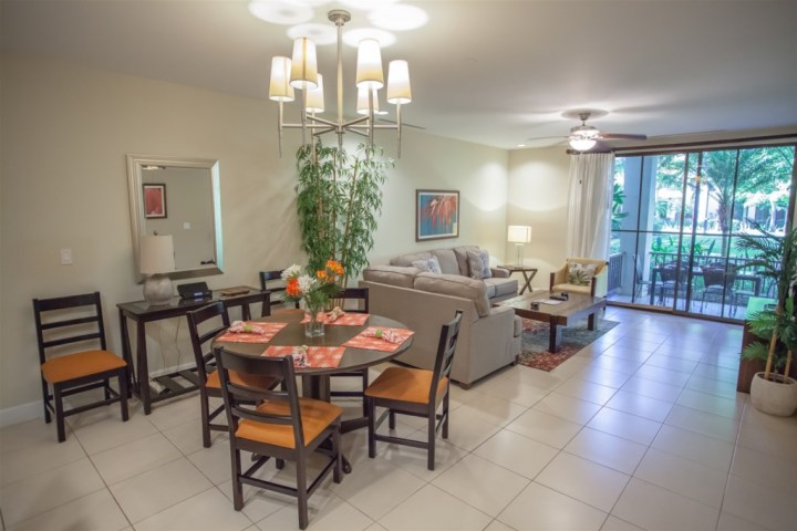Modern living room with dining set, cozy sofas, large window, and indoor plants.