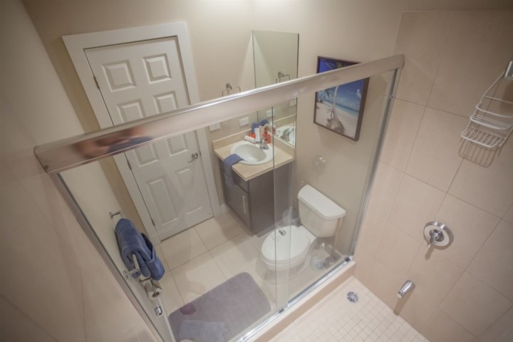 Bathroom with glass shower, toilet, and sink, viewed from above.