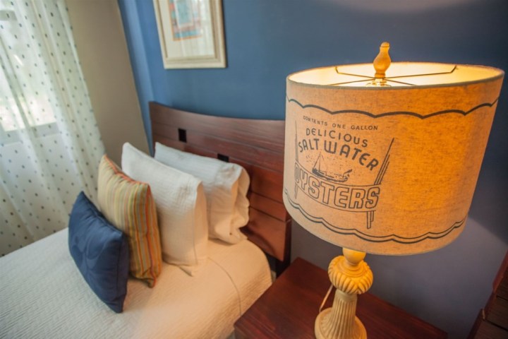 Bedroom with a blue wall, bed, pillows, and lamp with 'Saltwater Oysters' text.
