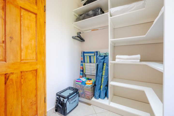Open closet with shelves, folded towels, and beach gear storage.