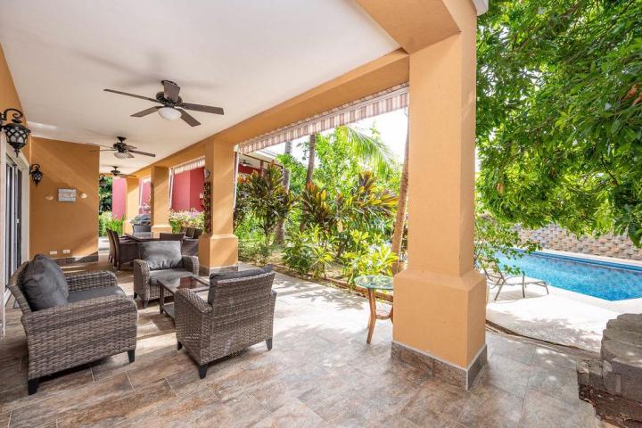 Covered patio with wicker furniture overlooking pool and garden.