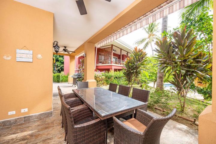 Outdoor patio with wicker dining set, ceiling fans, and garden view.