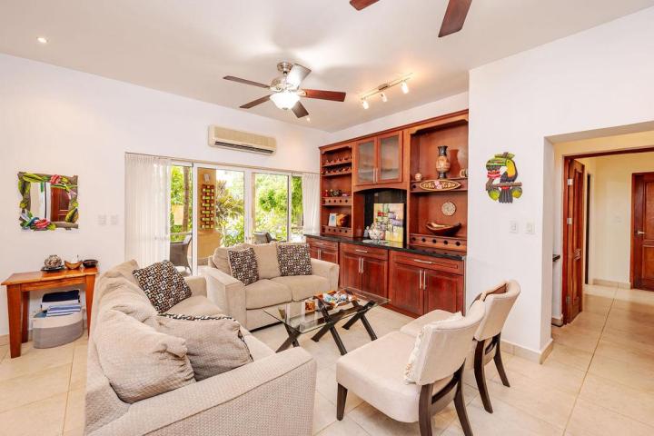 Cozy living room with beige sofas, glass coffee table, and wooden wall unit, overlooking a garden.