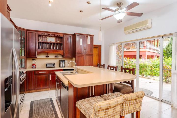 Modern kitchen with island, wooden cabinets, and large sliding doors leading to garden.