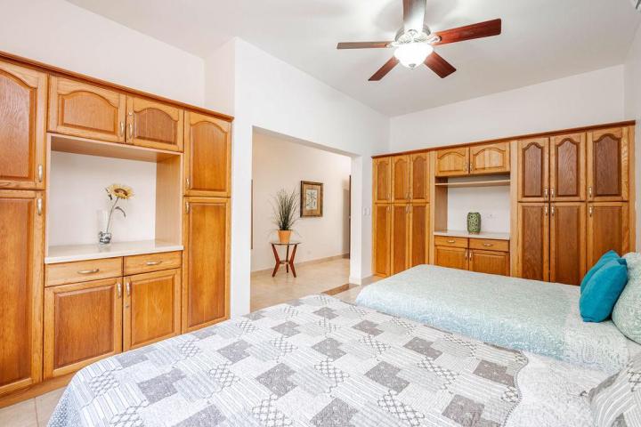 Bedroom with two beds, wooden cabinets, and a ceiling fan.