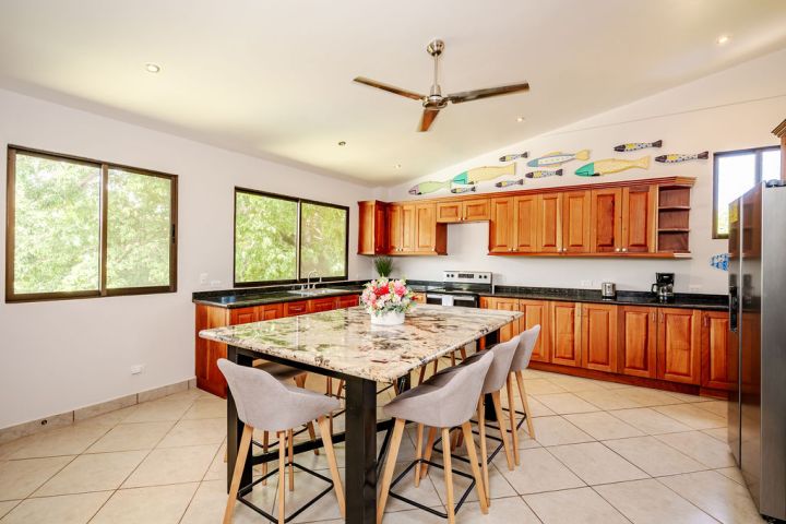 Spacious kitchen with wooden cabinets, marble island, and ceiling fan, decorated with colorful fish wall art.
