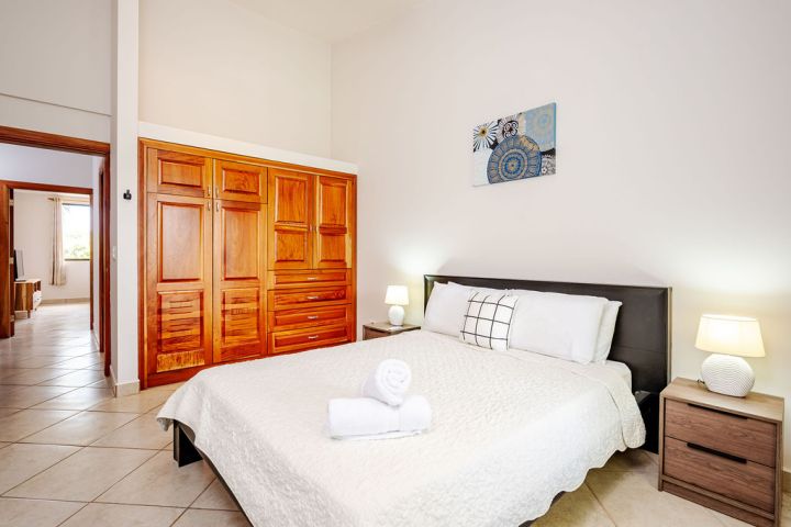 Bedroom with bed, nightstands, lamps, and wooden closet.