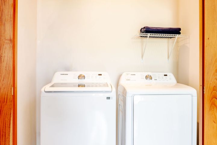 Washer and dryer in a laundry room with wooden doors and a shelf above.