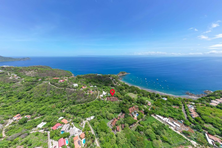 Aerial view of a coastal area with lush greenery and a clear blue sea.
