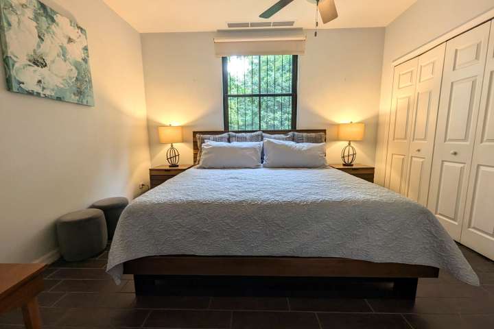 Bedroom with a large bed, two nightstands with lamps, and a ceiling fan.
