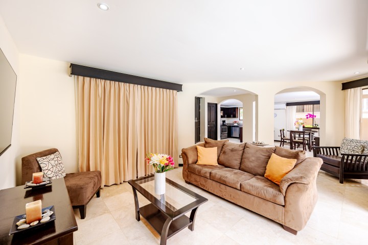 Spacious living room with brown couch, coffee table, and dining area visible through archways.