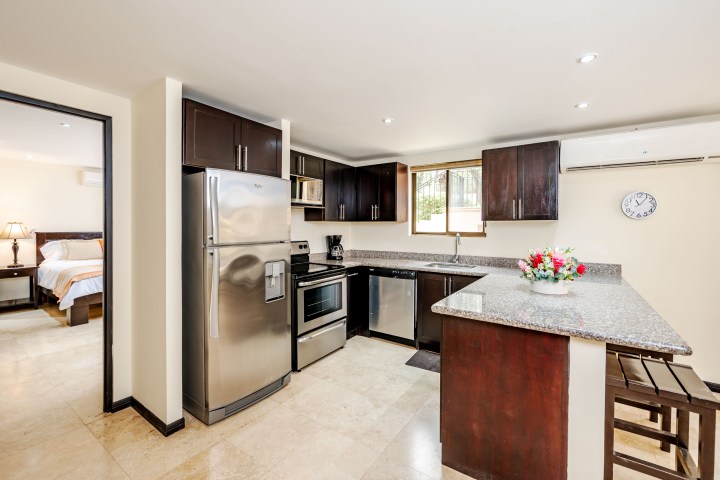 Modern kitchen with stainless steel appliances, granite countertop, and adjacent bedroom view.