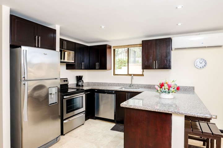 Modern kitchen with dark wood cabinets, stainless appliances, and granite countertops.
