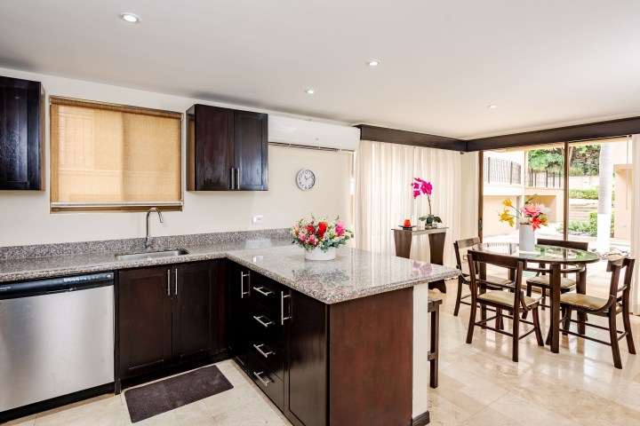 Modern kitchen with dark cabinets, granite countertops, dining table, and glass doors to patio.
