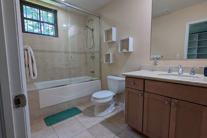 Bathroom with bathtub, toilet, wooden vanity, and tiled floor.