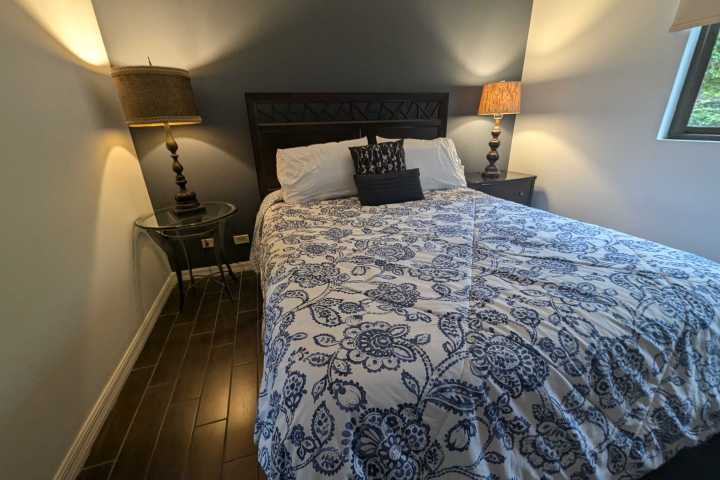 Bedroom with patterned bedspread, bedside tables, lamps, and a small window.