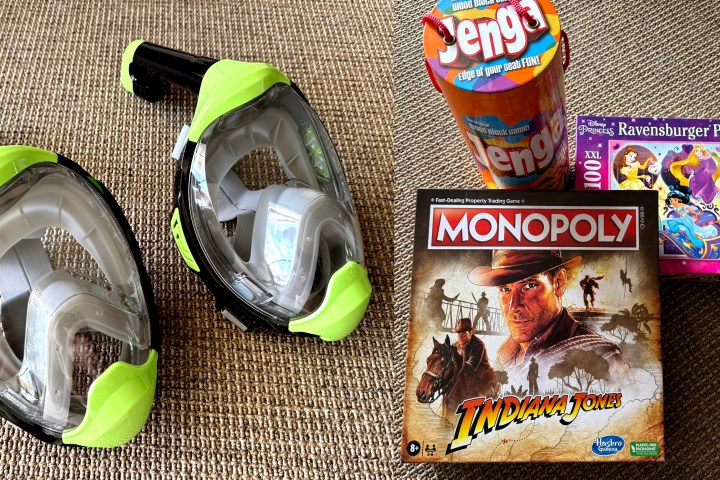 Two snorkel masks, Jenga, Indiana Jones Monopoly, and a Ravensburger puzzle on a brown fabric surface.