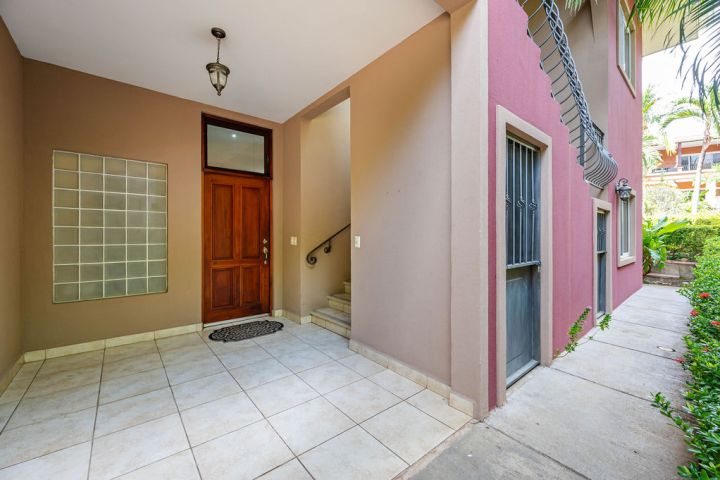 Entrance with wooden door, tiled floor, and staircase in a residential building.