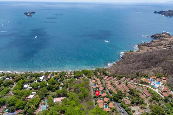 Aerial view of coastline with ocean, beaches, greenery, and buildings.