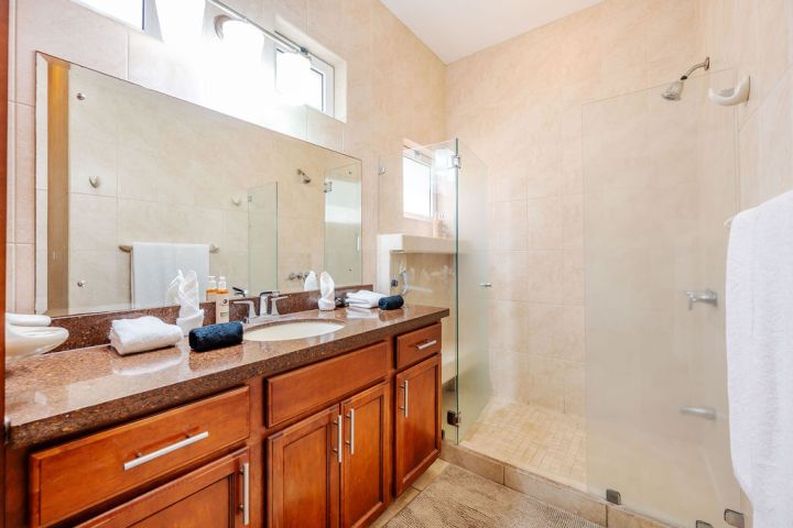 Modern bathroom with wood cabinets, glass shower, and mirror.