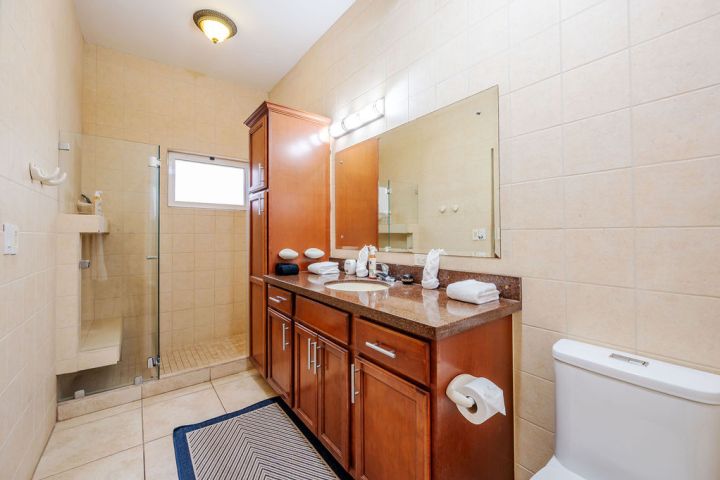 Bathroom with wooden vanity, large mirror, shower, and tiled walls.