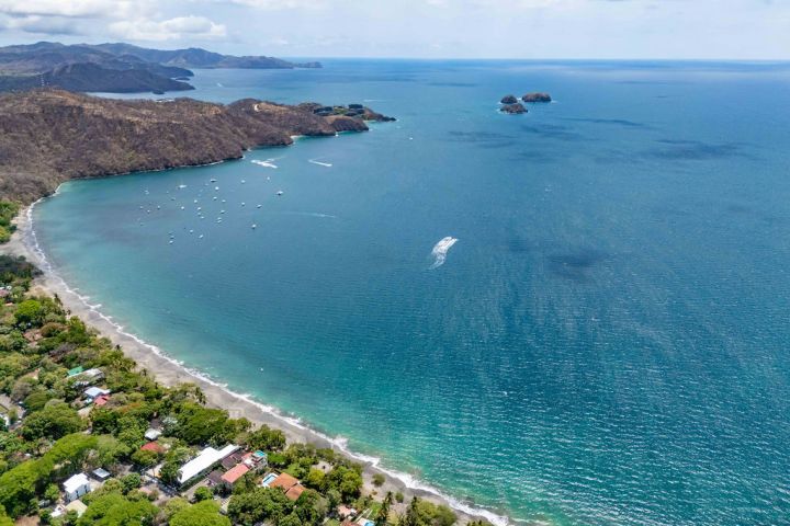 Aerial view of a coastal landscape with blue ocean and green shoreline.