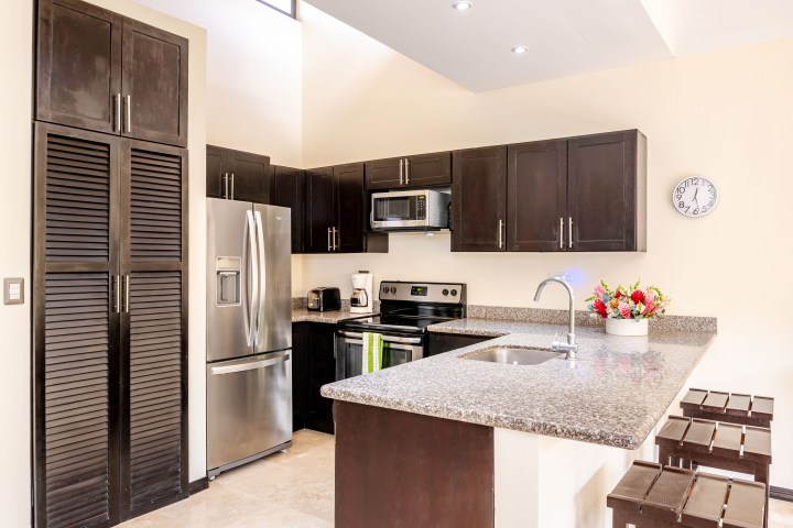 Modern kitchen with dark cabinets, stainless appliances, and granite countertops.