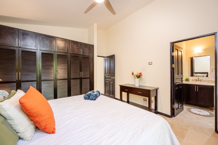 Bedroom with dark wood furniture, orange pillows, and an ensuite bathroom.