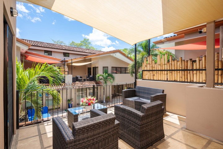 Outdoor patio with wicker furniture, bamboo decor, and overhead sunshades at a tropical villa.