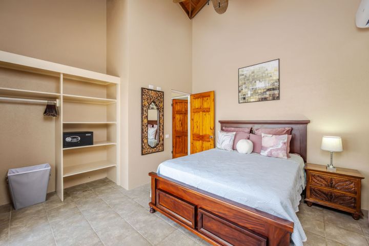 Bedroom with wooden bed, nightstand, open closet, wall art, and mirror.