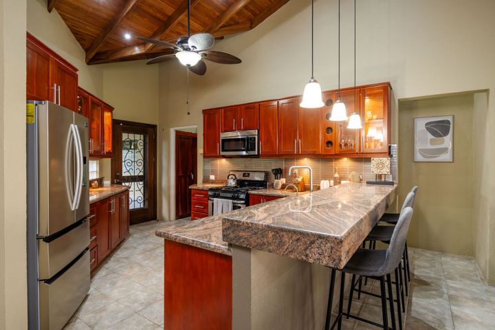 Modern kitchen with wood cabinets, granite countertops, stainless steel appliances, and pendant lighting.