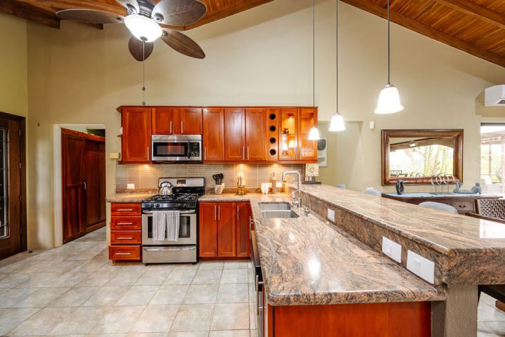 Spacious kitchen with wood cabinets, granite counters, and stainless steel appliances under a ceiling fan.