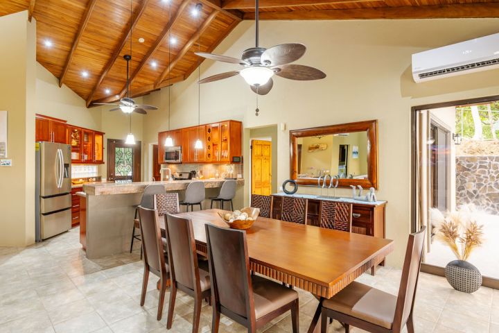 Spacious kitchen and dining area with wooden ceiling, wooden furniture, and modern appliances.